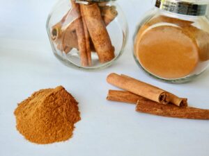 Close-up of cinnamon sticks and powder in jars on a white background.