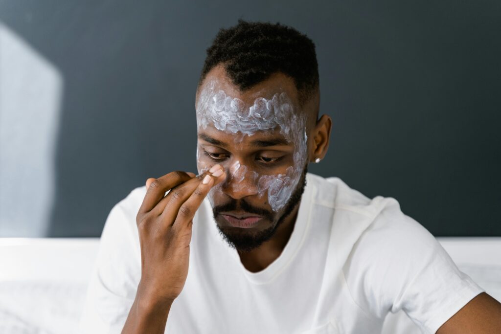 African American man applying facial cream, focusing on self-care and skin health.