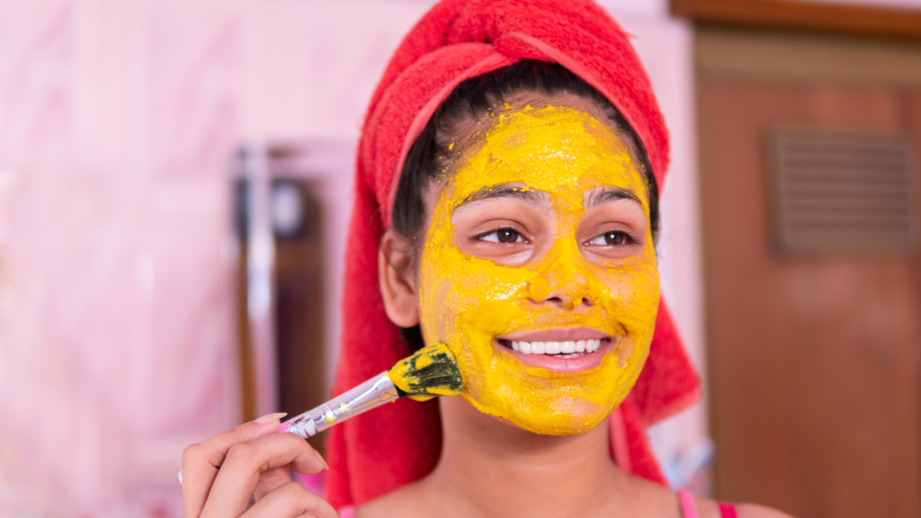 woman applying turmeric diy face mask with a brush
